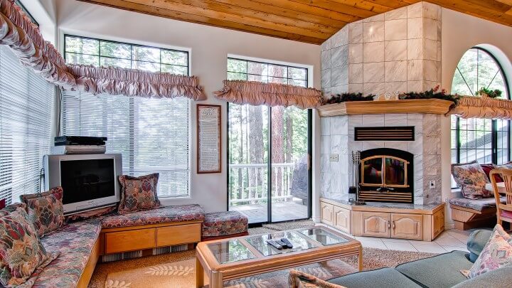 living room with stone fireplace and tall balcony doors