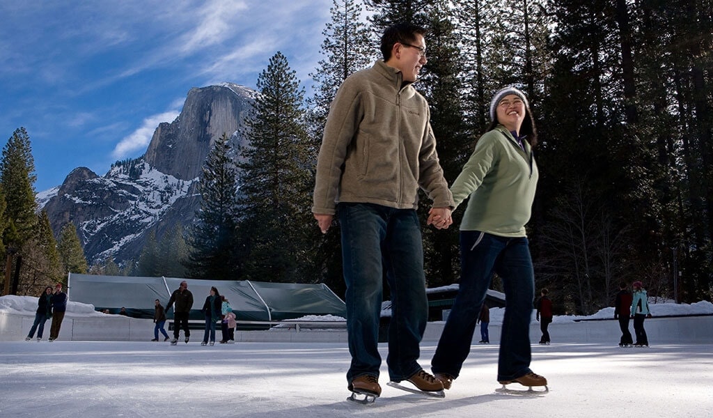 Couple ice skating at Curry Village beneath Half Dome