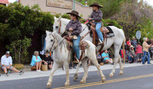 Two kids riding horses in a parade