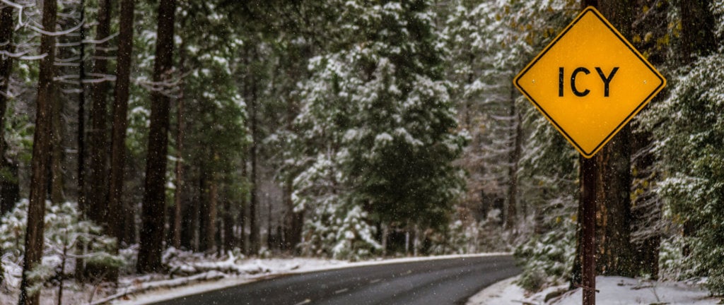 Snowy Yosemite road in winter with icy sign