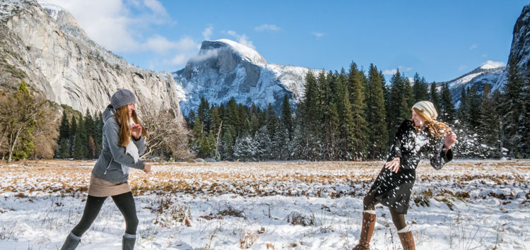 Women having a snowball fight in Ahwahnee Meadow with Half Dome behind.