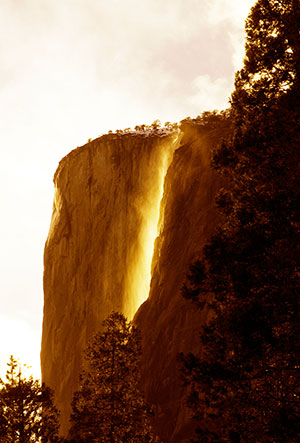 Horsetail fall flows bright against the dark cliffs behind