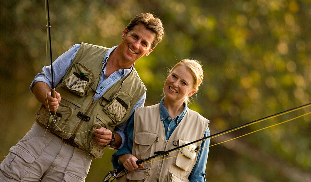 couple with fishing vests and fishing rod