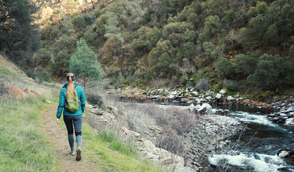 Woman walking a trail next to the Merced River