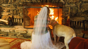 Bride and her dog in front of a fire