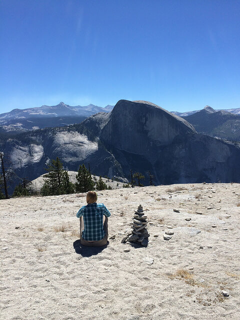 Hiker on North Dome looking at Half Dome