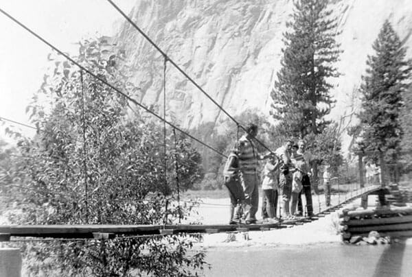 Historic image of a family lined up on the narrow swinging bridge in Yosemite Valley