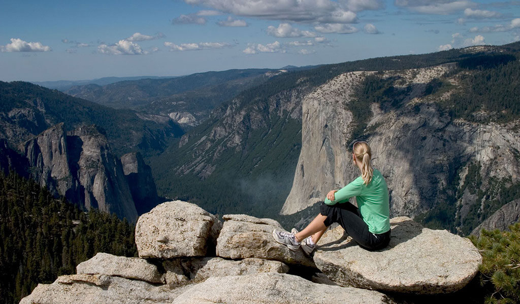 Woman sitting on Sentinel Dome with view of El Capitan