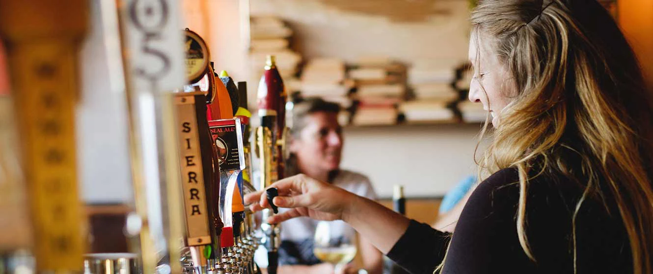 Woman pouring beer from tap at a Yosemite restaurant, The Alley Bar.