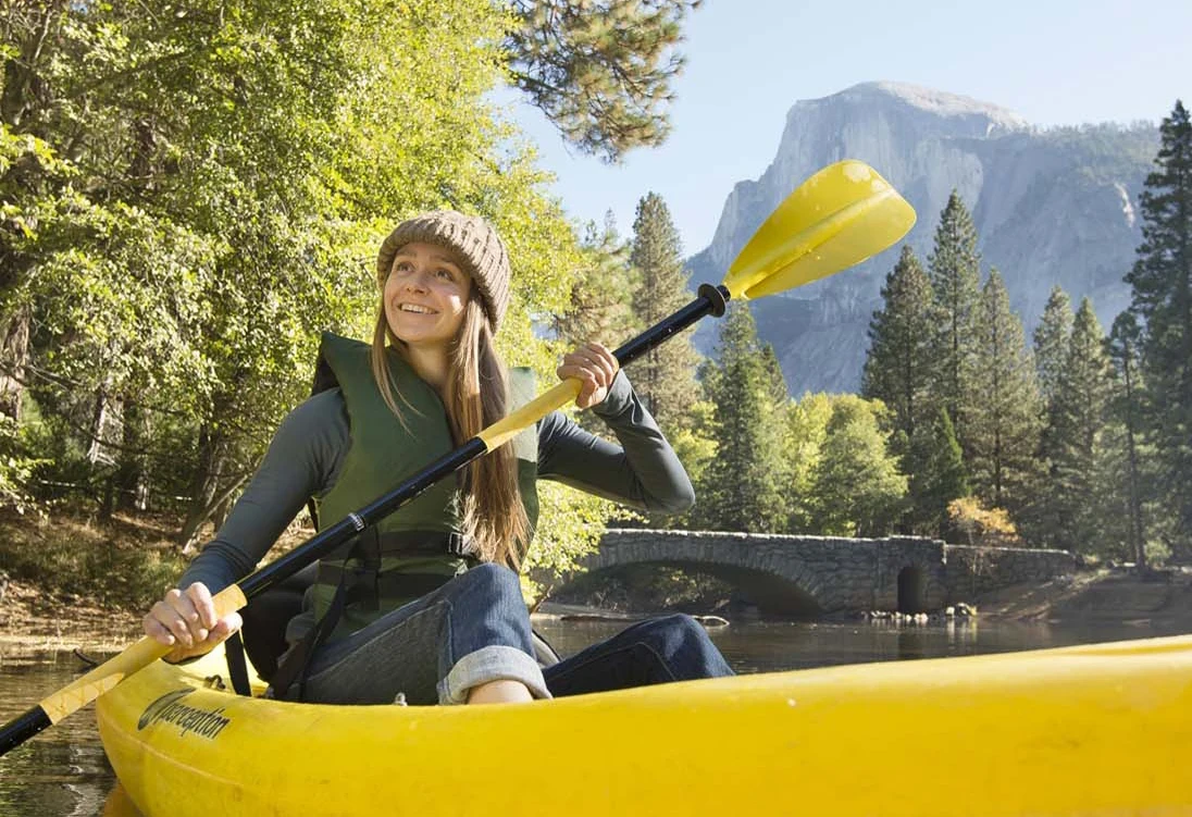 Woman kayaking in river with mountain landscape