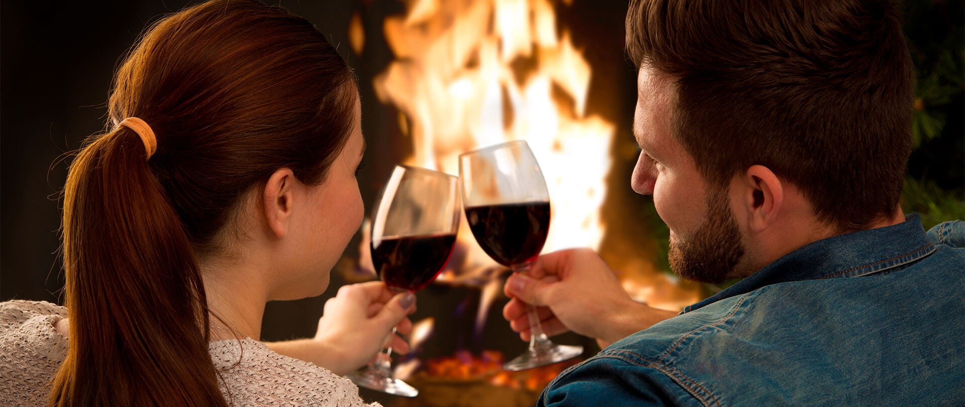 a couple toasting the new year together in front of a fireplace