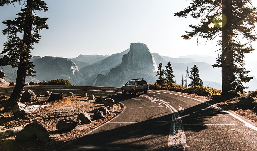 a car taking the u-bend in glacier point road with half dome in the background
