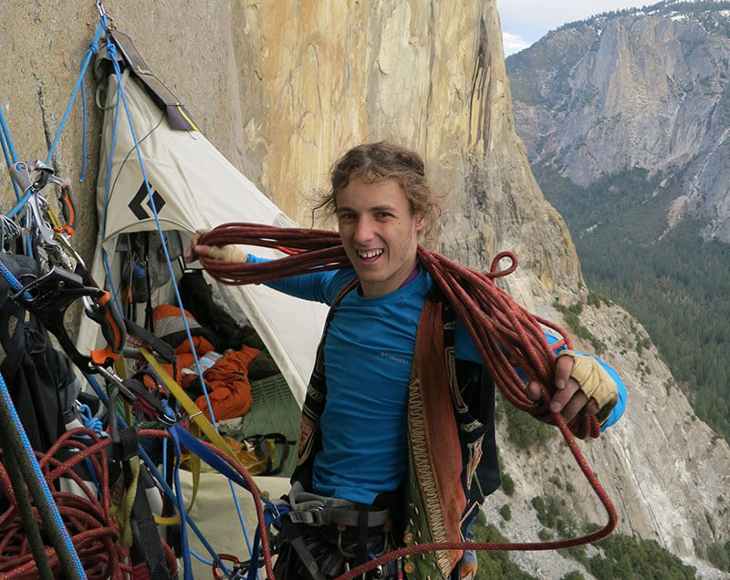 Climber Ryan Sheridan coils a rope high on El Capitan. Behind him you can see a portaledge where climbers spend the night.