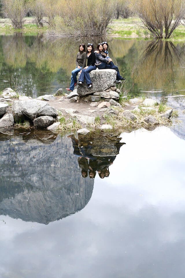 4 women pose for a photo on a rock in irror lake