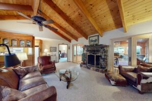 living room with stone fireplace and wood beams