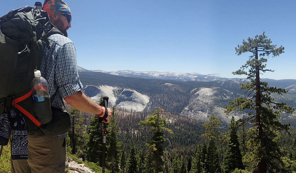 Backpacker looking out over granite domes near Clouds Rest