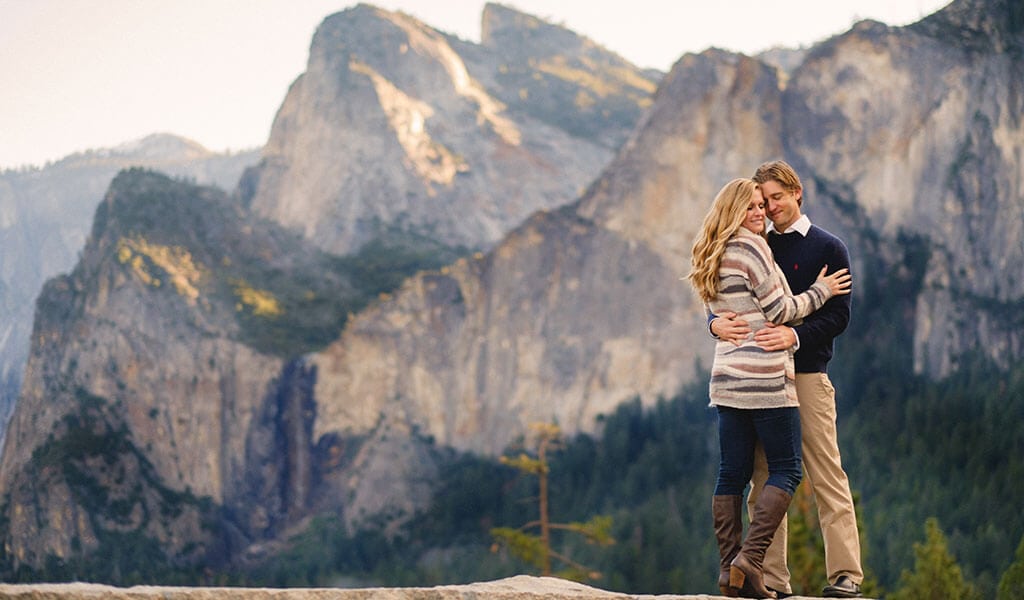 Couple standing at Tunnel View with Yosemite Valley behind them.