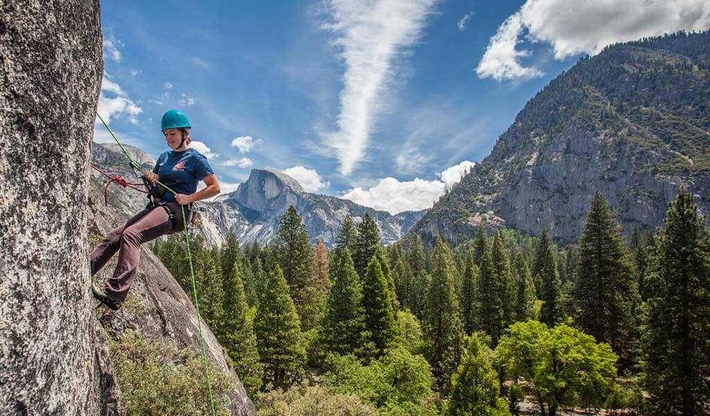 Young climber learning to rappel in Yosemite Valley with Half Dome in the background