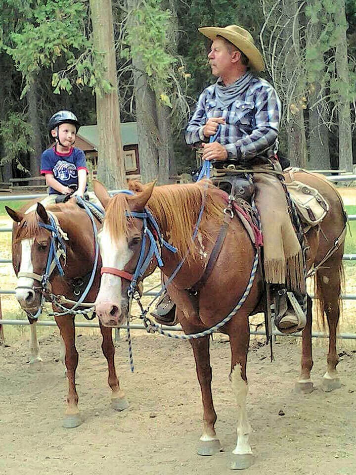 boy riding with cowboy at Yosemite Trails