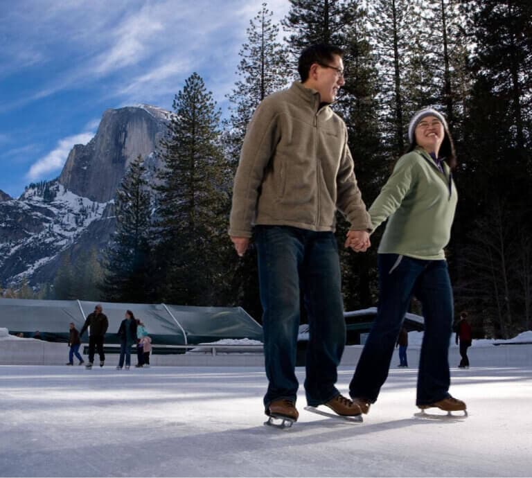 Couple skating in Curry Village with Half Dome behind