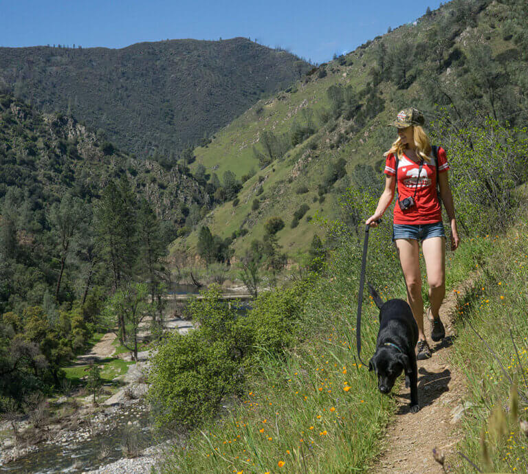 woman hiking with her dog above the river at Hite Cove