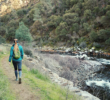 woman hiking along the side of the Merced River