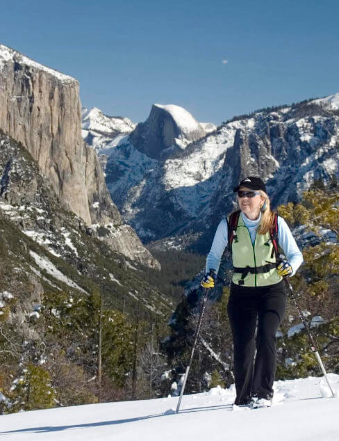 Woman snowshoeing with El Capitan and Half Dome in the background