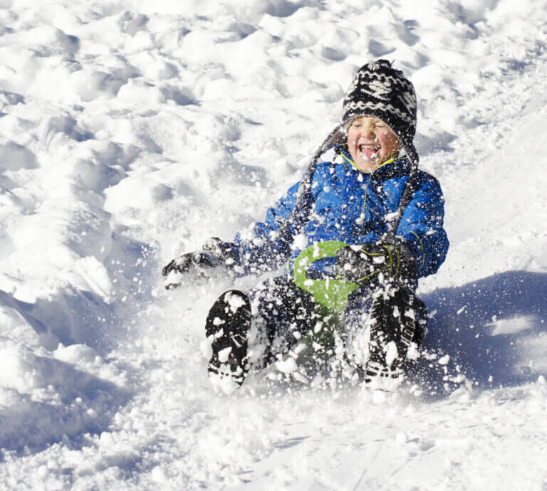 Child sledding with huge smile