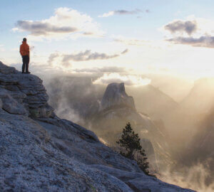 Hiker on Cloud's Rest looking at Half Dome through the clouds