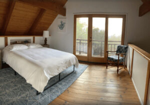 bedroom with sloped wood ceiling and balcony