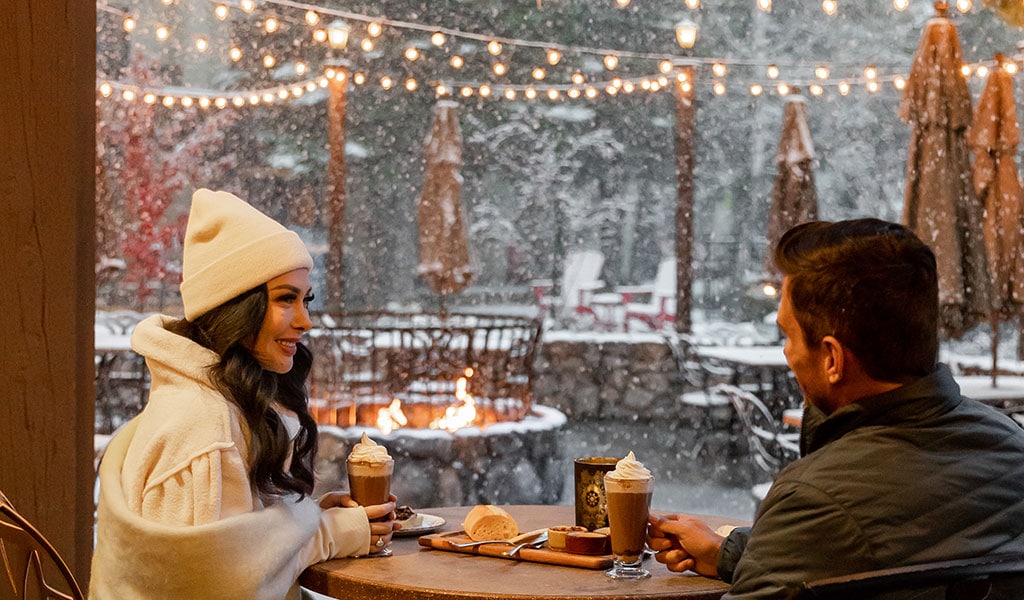 Couple enjoying hot drinks at while the snow falls