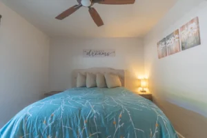 bedroom with queen bed, fan and window