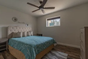 bedroom with queen bed, fan and window