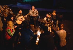 People gathering around the campfire at the Yosemite Bug Rustic Mountain Resort