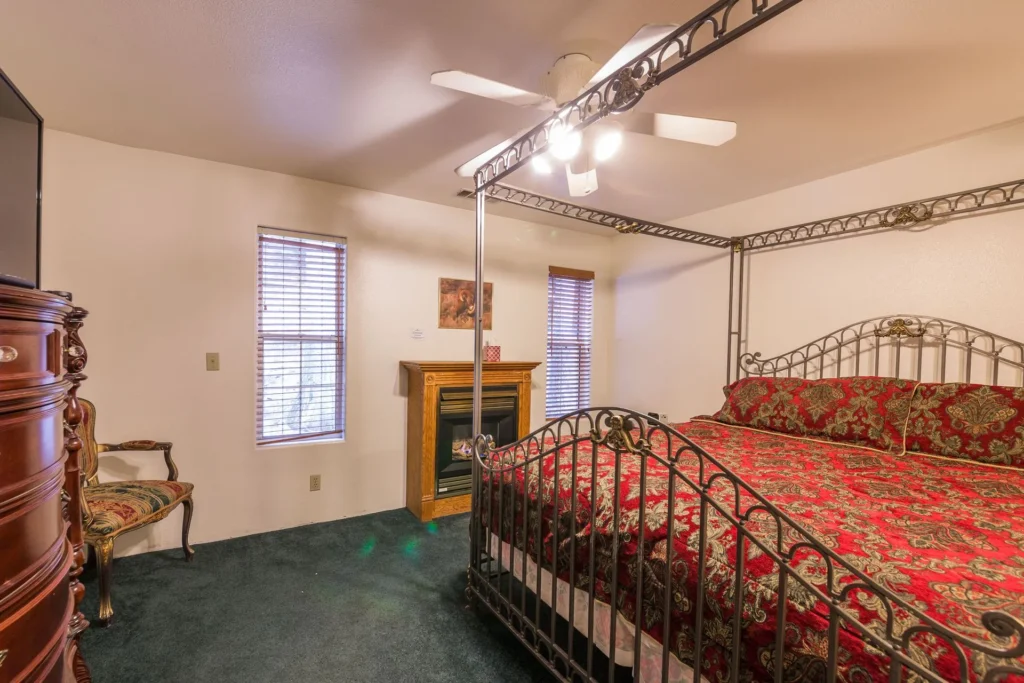 bedroom with four poster bed and electric fireplace