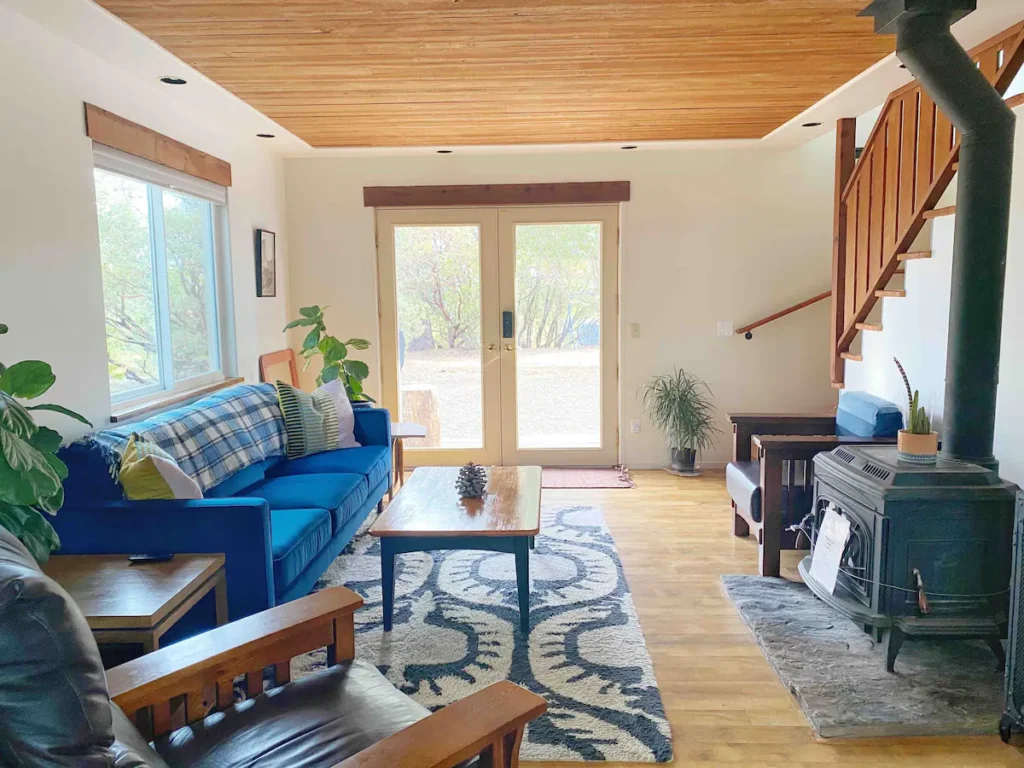 living room with wood ceiling, blue couch and wood stove