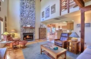 living room with tall ceilings and loft, stone fireplace and couches
