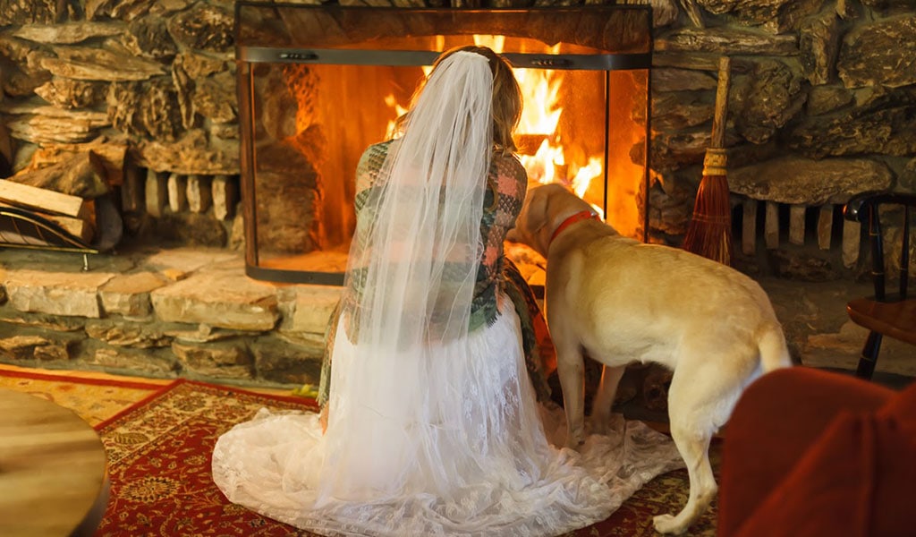 Bride crouching by fire with her dog
