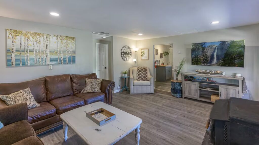living room with television, couches, and wood stove