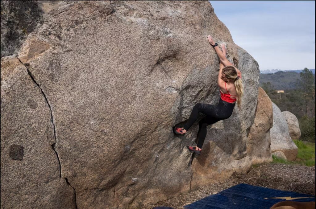 woman climbing on boulder