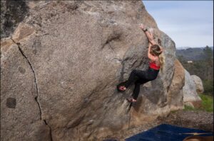 woman climbing on boulder